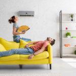 exhausted man lying on yellow sofa under air conditioner near wo